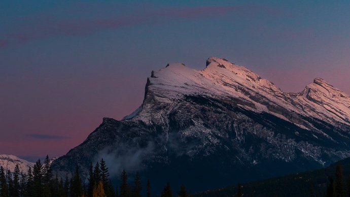 Snowy mountain under clear sky at dusk